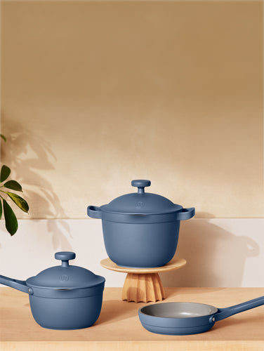 Three small blue pans on a wooden countertop