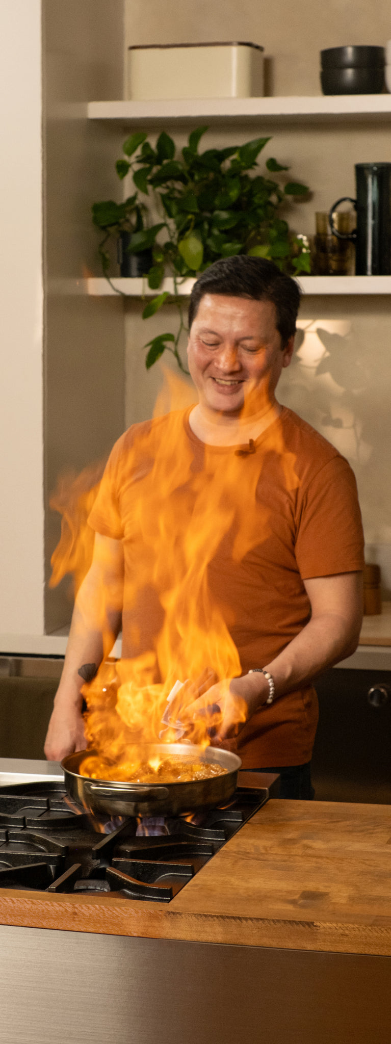 Person cooking with a flaming pan in a kitchen