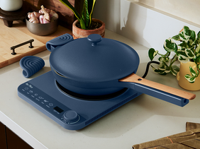Blue frying pan with lid on an electric hot plate in a kitchen setting