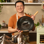 Man holding a black frying pan in a kitchen setting