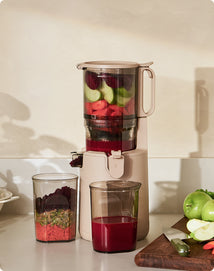 Juicer with ingredients and two glasses on a countertop
