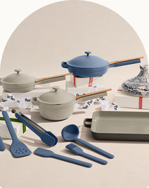 Set of kitchen utensils and cookware including pots, pans, and spatulas on a neutral background.