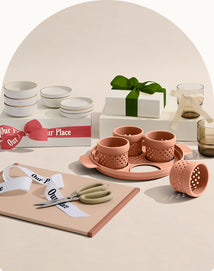 Set of ceramic items including cups, bowls, and a tray on a neutral background with 'Our Place' branding.