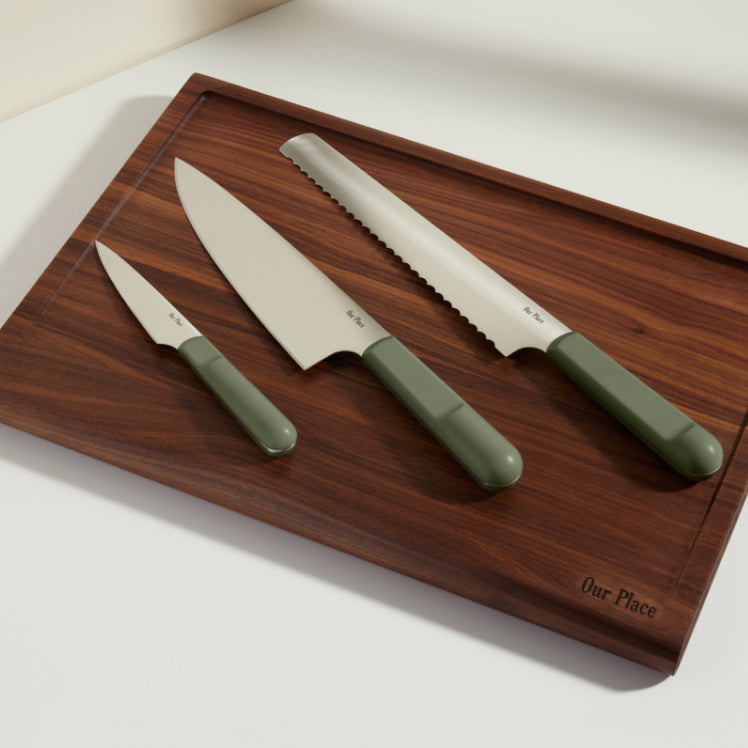 green chefs knife, serrated knife, and paring knife on walnut cutting board