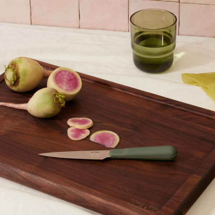 green precise paring knife on walnut cutting board with raddishs