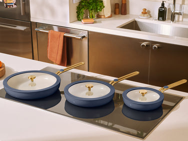 Three blue ceramic cookware items on a stovetop in a kitchen setting.