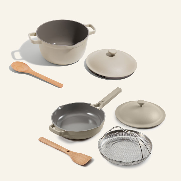 Set of cookware including pots, pans, and lids on a white background
