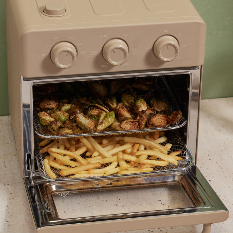 Beige toaster oven with food inside on a countertop