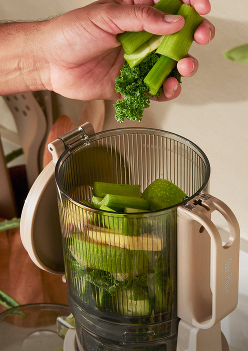 Person using a vegetable chopper to chop green vegetables.