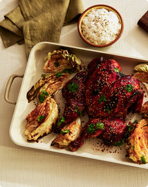 Plated dish of roasted vegetables and meat with a side of rice on a beige tablecloth.