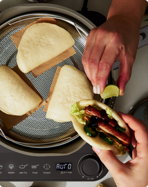 Person assembling a sandwich with a toaster in the background