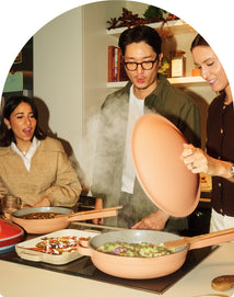 People cooking together in a kitchen with a pink pan.