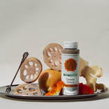 Bottle of 'Bowlcut' creamy sauce on a plate with sliced lotus root and other ingredients.