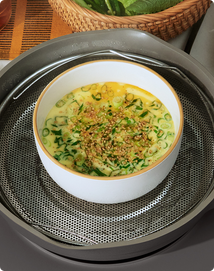 White bowl with green vegetable dish on a metallic surface