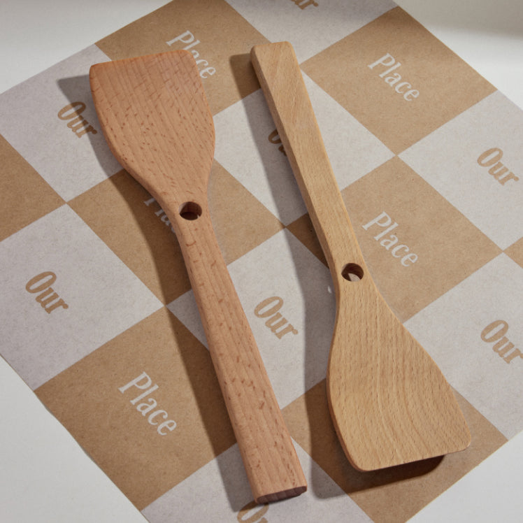 Two beechwood spatulas resting on an our place branded background