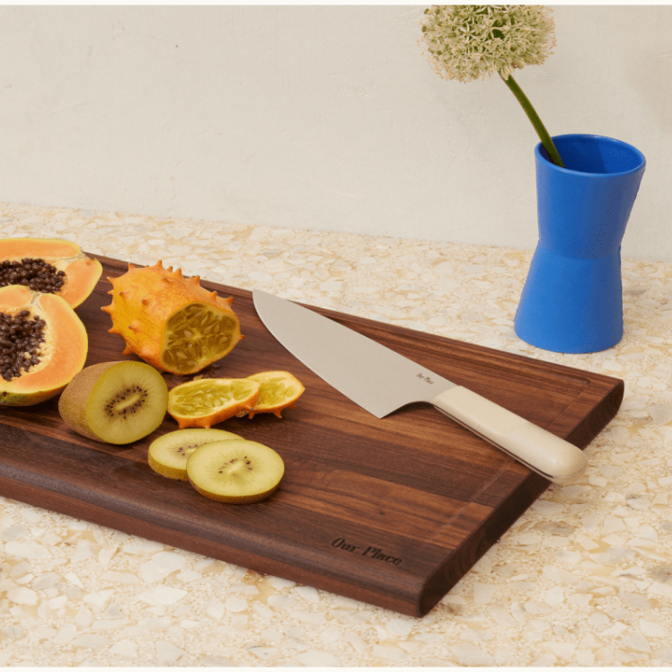 Beige Everyday Chef's Knife on top of the Walnut Cutting Board with fruit