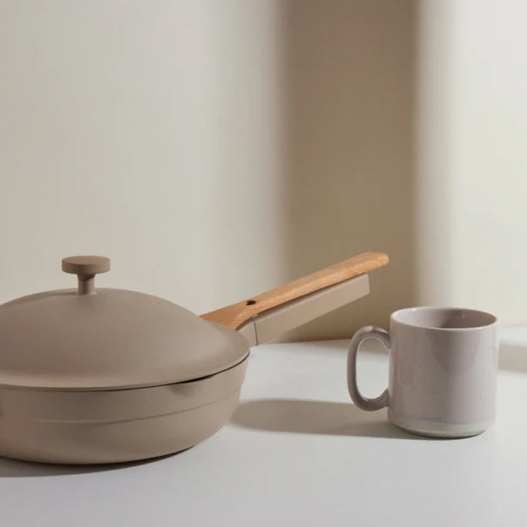 A beige mug next to a beige Always Pan