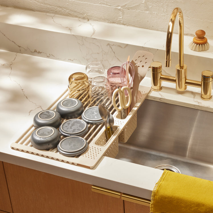 beige roll out rack on sink with dishes