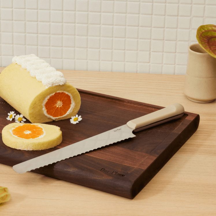 Beige Serrated Slicing Knife on top of the Walnut Cutting Board with dessert