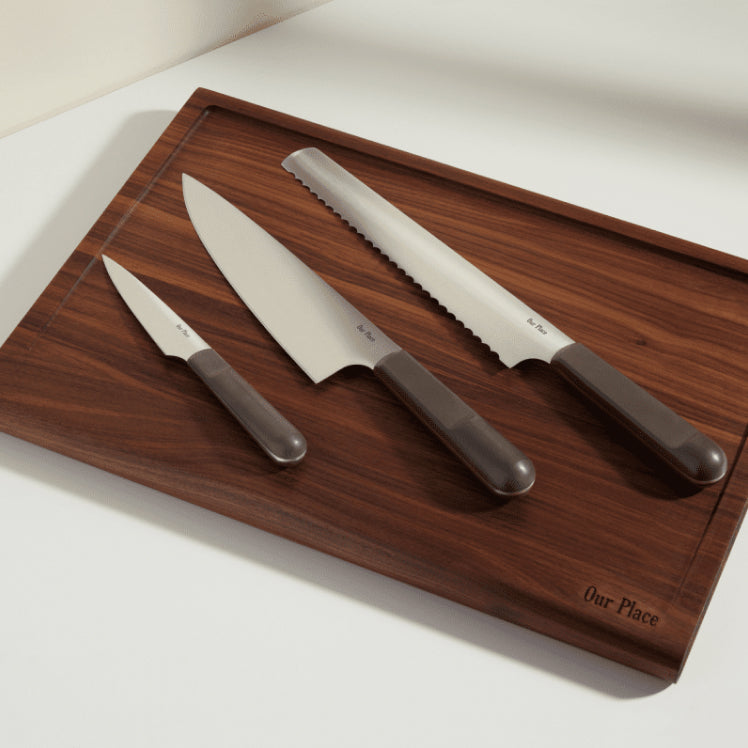 black chefs knife, serrated knife, and paring knife on walnut cutting board