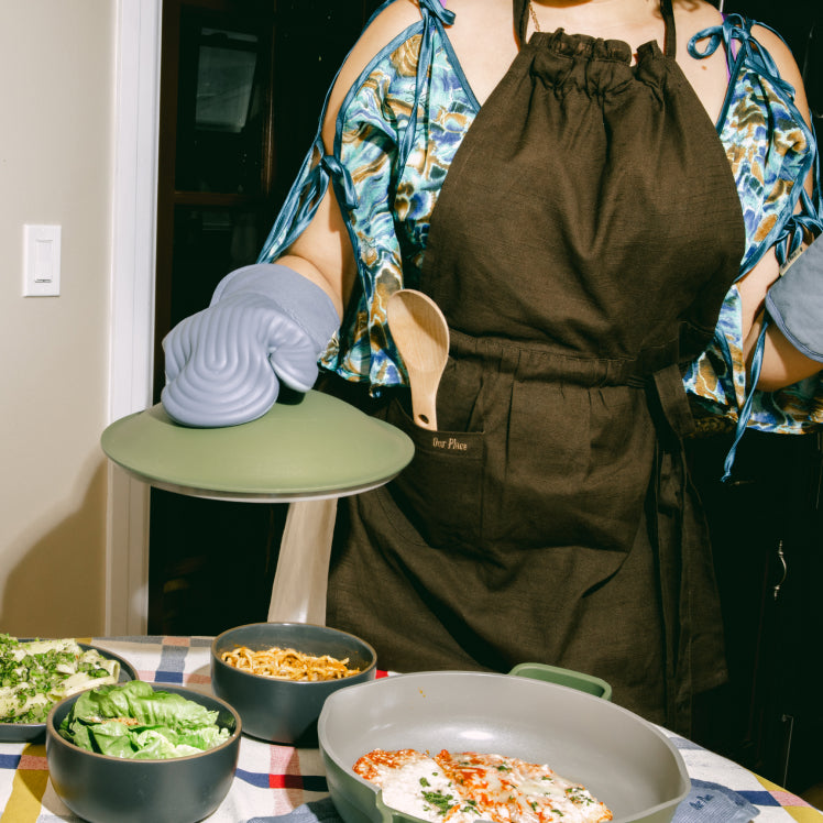 A chef wearing a black Hosting Apron serves a meal