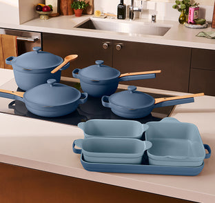 Set of blue cookware on a kitchen counter with a stove in the background