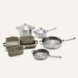 The Titanium Pro Cookware + Bakeware Set 2.0 includes a collection of high-performance metal pots with lids, two metal skillets, and several rectangular ceramic bakeware dishes.