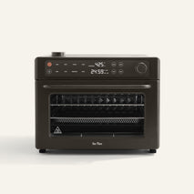 A countertop air fryer oven with a digital display showing 425°F and 24:59. The oven is dark-colored and has control knobs, buttons, and multiple internal racks.