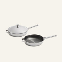 A Titanium Pro Always Pan Duo 2.0 featuring a lidded white sauté pan and an open stainless steel skillet with matching handles, crafted from non-toxic materials.