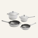 Titanium Pro Cookware Set 2.0 featuring two lidded stainless steel pots and two frying pans with silver handles and light gray exterior surfaces.