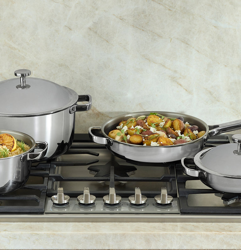 Set of titanium cookware on a gas stove with food inside