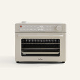 A beige countertop air fryer oven with digital display shows 425°F and 24:59. The appliance has a windowed door and control knobs, with trays visible inside.
