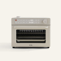 A beige countertop air fryer oven with digital display shows 425°F and 24:59. The appliance has a windowed door and control knobs, with trays visible inside.