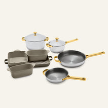 Titanium Pro Cookware + Bakeware Set 2.0 including two lidded pots, two frying pans, and three ceramic bakeware dishes with gold-toned handles and lids.