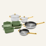 Titanium Pro Cookware + Bakeware Set 2.0 featuring silver pots and pans with gold-toned handles and lids, alongside green ceramic bakeware.