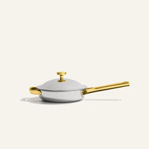 A light gray Titanium Always Pan Pro 8.5″ 2.0 with a matching lid and shiny gold handles and knob.