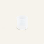 A small, clear plastic beaker with a spout, placed on a plain light background.
