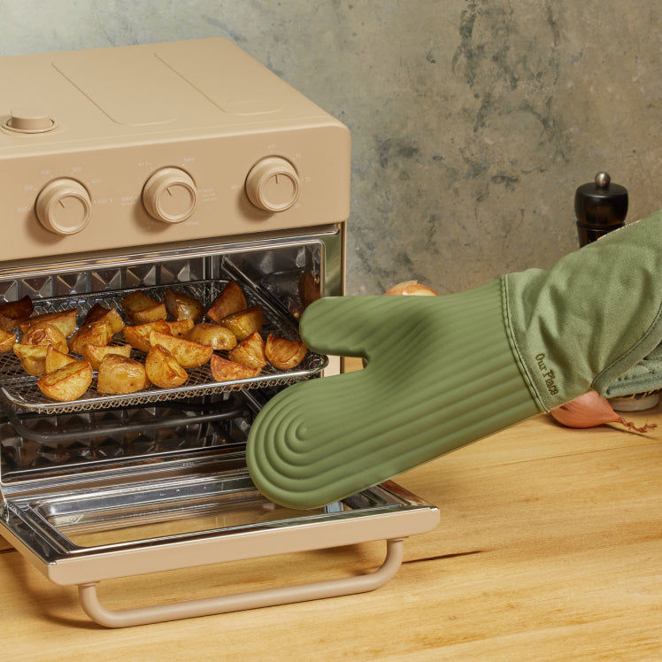 Using green Hot Mitts to remove crispy potatoes from a beige Wonder Oven