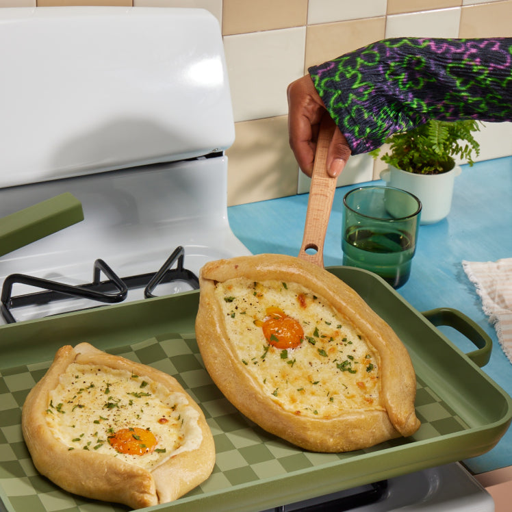 Cooking an egg pastry on the stovetop with green Oven Mats and green Griddle Pan