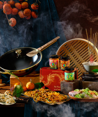 A smoky, dramatic scene featuring a wok, steaming dishes, noodles, sauces, candles, a gourd, and traditional Asian decor, evoking the ambiance of an Asian kitchen rich with flavors and culture.