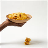 Hand holding a bowl of potato chips with a smaller pile on a white background