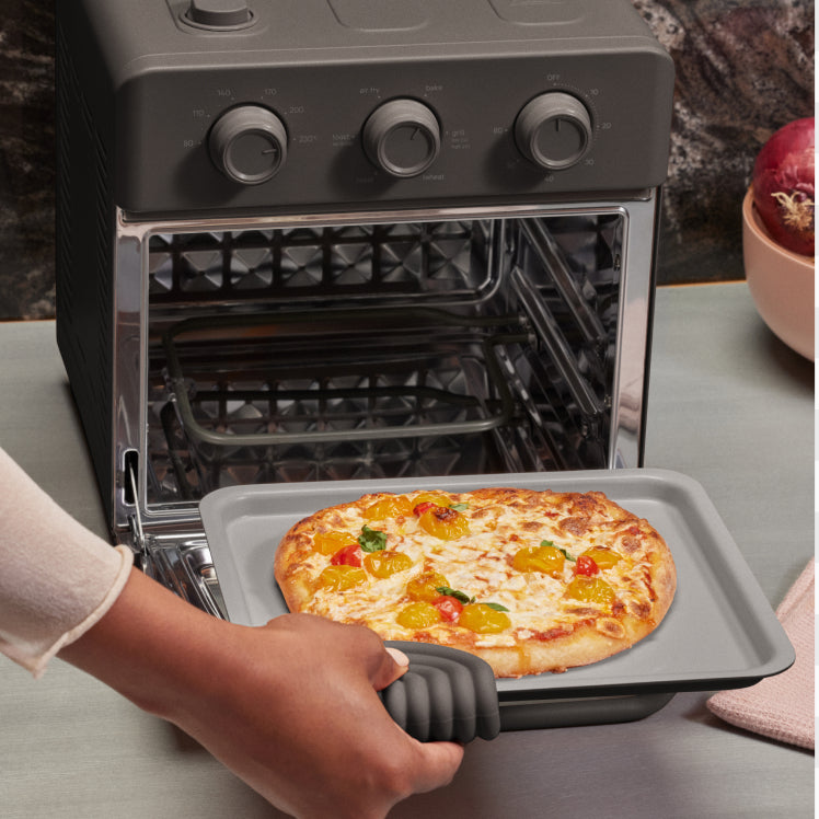Person taking a pizza out of an open oven with a tray.