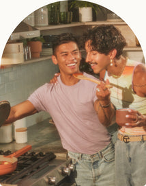 two people gathered by stove cooking with pink always pan