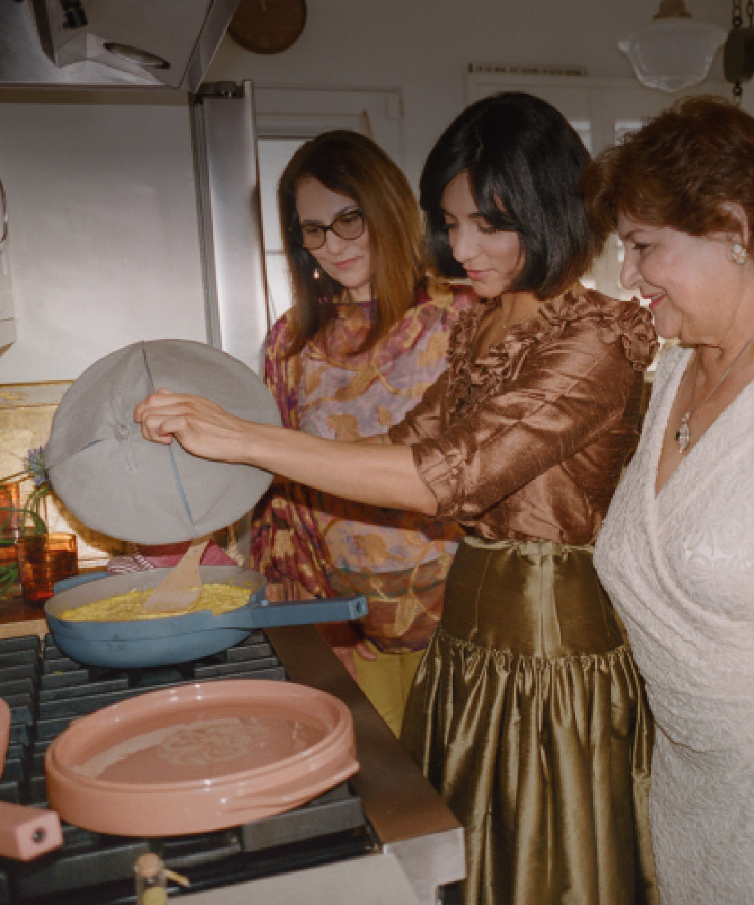 group of three women around the stove cooking with blue non toxic ceramic nonstick always pan and pink flipping platter