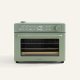 A sage green countertop oven with digital controls and display showing 425°F and 24:59. It has a windowed door and a tray inside.
