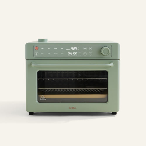 A sage green countertop oven with digital controls and display showing 425°F and 24:59. It has a windowed door and a tray inside.