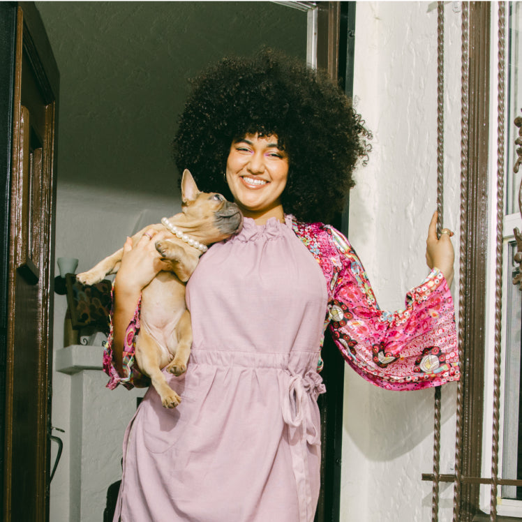 A chef holding a dog wears a purple Hosting Apron