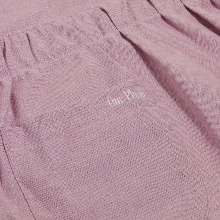 Our Place logo embroidered on the pocket of a purple Hosting Apron