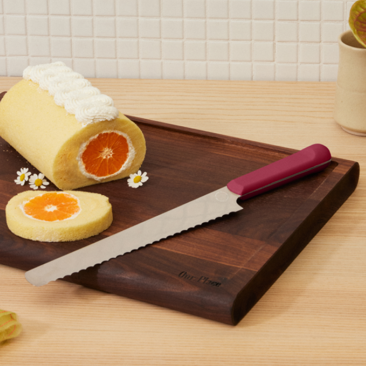 Red Serrated Slicing Knife on top of the Walnut Cutting Board with dessert