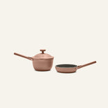 The Tiny Cookware Duo, featuring a matching pink saucepan with lid and frying pan, is displayed against a plain light background.